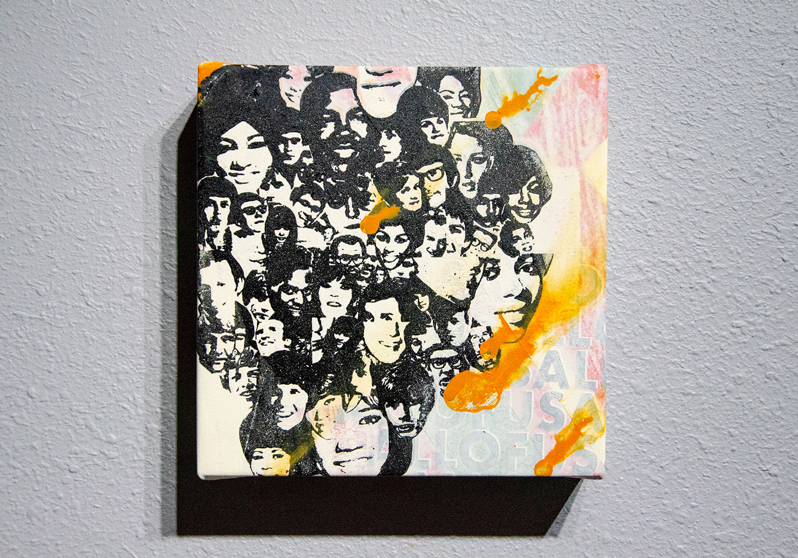 A piece of abstract art featuring a screen print with geometric patterns on clear vinyl stretched around a wood panel, predominantly in black, white, and orange colors.